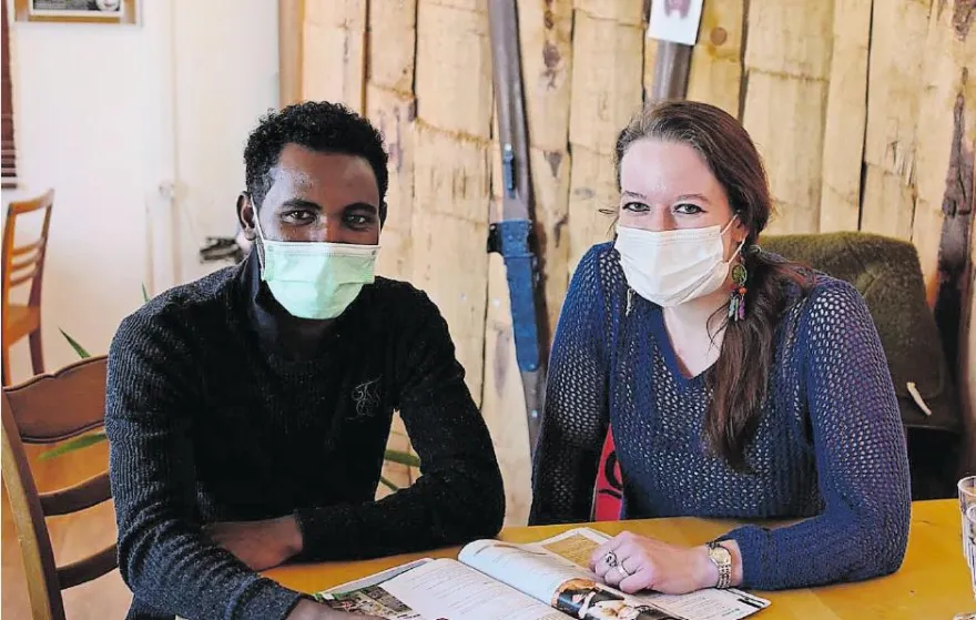 Junger Migrant sitzt mit seiner Mentorin an einem Tisch
